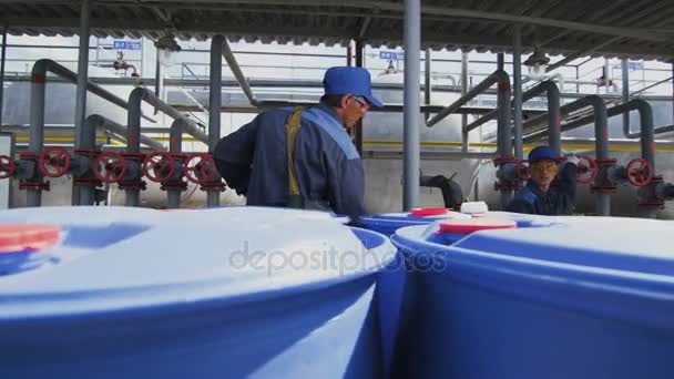 カザン タタールスタン共和国 ロシア連邦 2018 クロス ボディー バッグの専門労働者上の塗りつぶしの巨大な青いタンク工場面積でパイプラインに対して金属パイプでカザンの — ストック動画