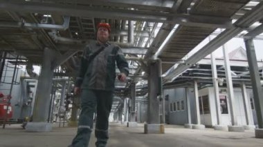 koruyucu kask içinde closeup ciddi çalışan petrol bitki yürür ve bilgi radyo sette iletir