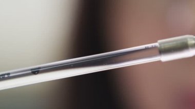 closeup küçük küresel ham petrol uzun laboratuar cam içine temiz su float kadın Yardımcısı elinde düştü.