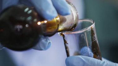 portre profesyonel asistan laboratuvar araştırma içinde uzun laboratuar cam içine ampul ham petrol dökülen