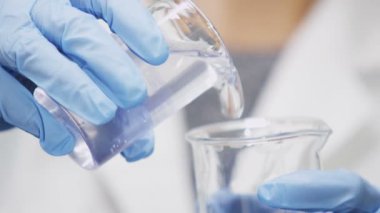 Mavi kauçuk eldiven ve önlük closeup bizzat boş ampul içine açık sümük laboratuvar araştırma tesisinde dökülen.