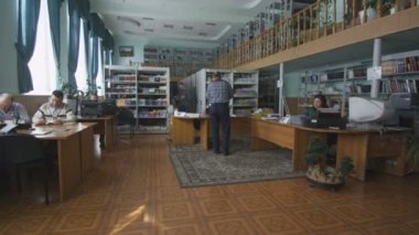 Kazan, Tataristan/Rusya - 23 Ağustos 2017: Closeup adam bıyık ile kitap alır ve veri kaydındaki 23 Ağustos kazan insanlar okuma arasında aşağı Kütüphane işçi yazıyor