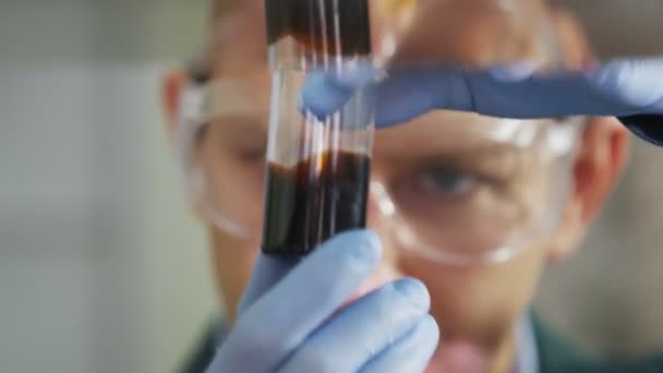カザン タタールスタン共和国 ロシア連邦 2017 保護メガネで幸せな男研究室助手をクローズ アップで見る電球モダンなテスト ラボで黒の原料油カザンで — ストック動画
