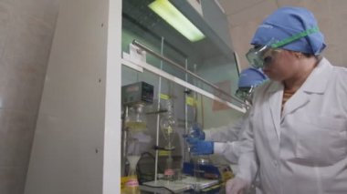 Kazan, Tataristan/Rusya - 23 Ağustos 2017: Yan görünümü kadınlarda beyaz palto ve koruyucu gözlük sarı sıvı ampuller güçlü cihaz üzerinde 23 Ağustos kazan test