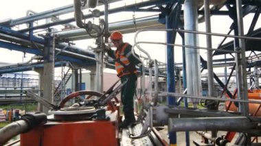 Kazan, Tataristan/Rusya - 22 Ağustos 2017: Turuncu yelek vasıflı işçi yağı ile boru hatları karşı metal zemin üzerinde 22 Ağustos kazan dolum tank kontrol eder