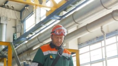 Kazan, Tataristan/Rusya - 22 Ağustos 2017: Profesyonel çalışan yeşil üniformalı merdivenlerden aşağı gider ve denetimleri metre veri kompresör üzerinde 22 Ağustos kazan basınç