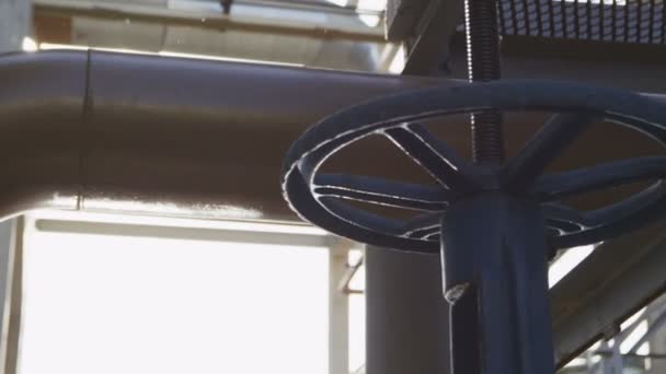 工場ワーク ショップで明るい太陽の光に対してガス パイプラインに大きな青い金属バルブ — ストック動画