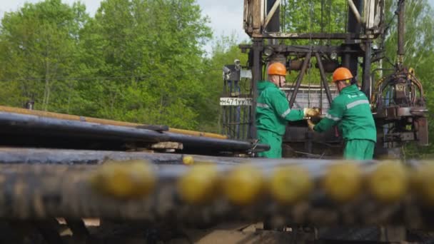 カザン タタールスタン ロシア 2018年4月17日 緑の制服とオレンジのヘルメットの石油企業の労働者は 4月17日にカザンで緑の木に対して掘削リグケーブルを修正します — ストック動画