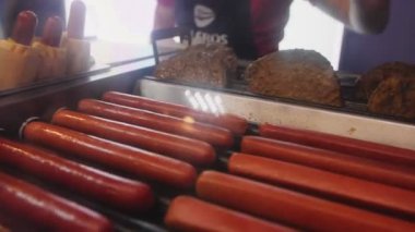 Şef fast food kafede ağır çekimde ızgaradan sosis alır.
