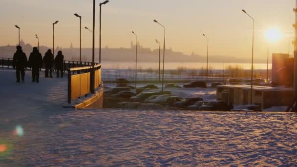 Ludzie chodzą ścieżką pokrytą śniegiem o zachodzie słońca — Wideo stockowe