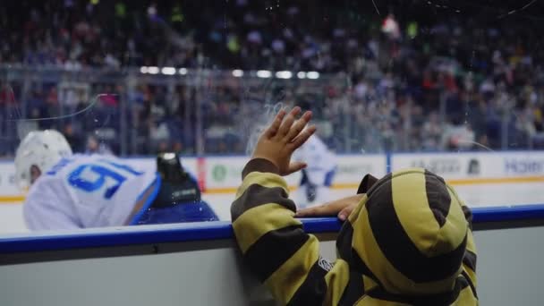 Kleine jongen tikt scherm kijken hockey wedstrijd op ijs arena — Stockvideo