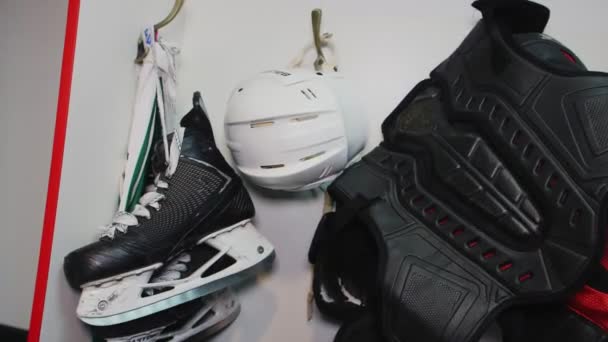 Hockey skates helmet and protective vest hang in team room — Stock Video