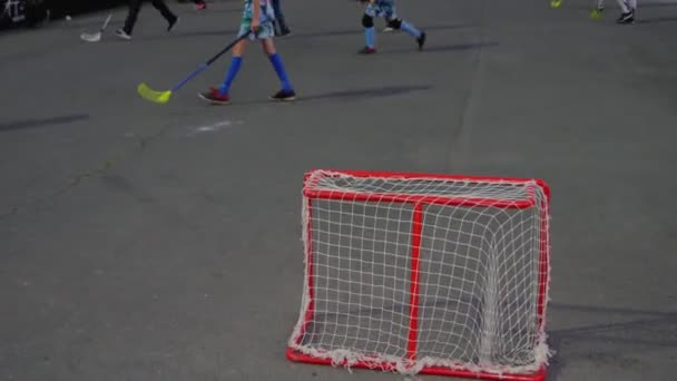 Les enfants jouent au hockey d'été sur un terrain asphalté près du stade — Video