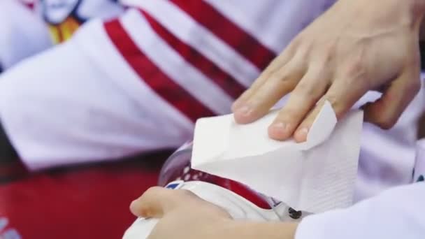 Хоккеист очищает маску каскада салфеткой крупным планом — стоковое видео
