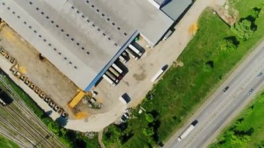 Güneşli bir günde demiryolu ve yolun yakınındaki depoyu kameralar çeviriyor.