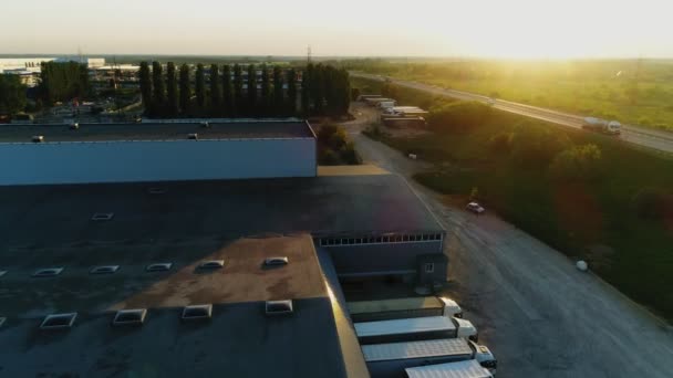 Jalan raya dengan mobil mengemudi dekat gudang besar saat matahari terbenam — Stok Video