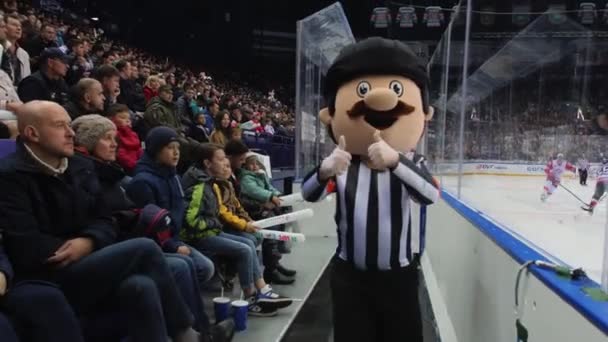 Mascot person in hockey judge suit runs by modern ice arena — Stock Video