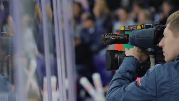 Телеоператор с камерой снимает хоккей на катке — стоковое видео