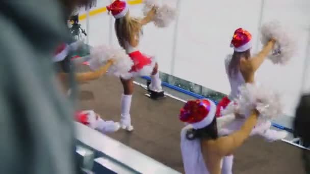 Черлидерши в Санта-Клаусе танцуют возле катка с видом сзади — стоковое видео