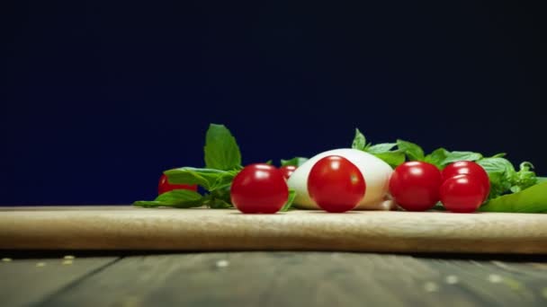 Rote Kirschtomaten fallen in Zeitlupe auf Holztisch — Stockvideo