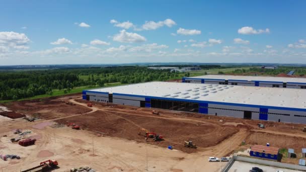 Carros dirigem ao longo de novo armazém no local de construção aérea — Vídeo de Stock