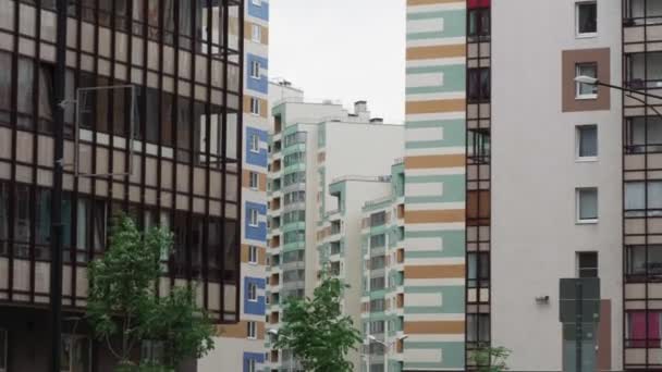 Árboles ondeados por el viento contra edificios de apartamentos cámara lenta — Vídeos de Stock