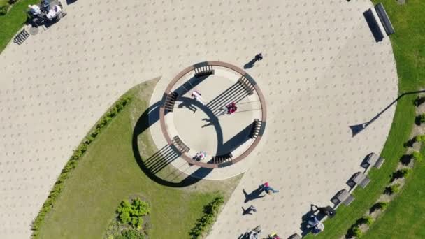 Камера поднимается над круглыми качелями в зеленом парке в солнечный день — стоковое видео