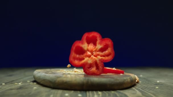 Rode paprika plakjes vallen neer op houten tafel slow motion — Stockvideo