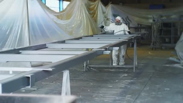 Empleado protegido utiliza pulverizador para pintar la carcasa en el taller — Vídeos de Stock