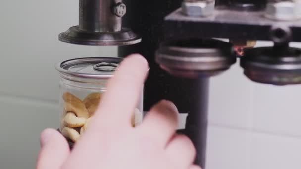 Werknemer sluit pot cashewnoten met dop op de werkplek — Stockvideo