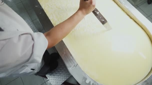 Homem em misturas uniformes queijo líquido em recipiente de metal perto — Vídeo de Stock