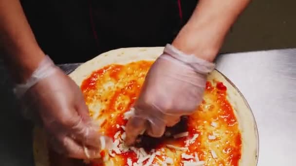 Mann fügt geriebenen Käse auf Pizzaboden mit Sauce Nahaufnahme hinzu — Stockvideo