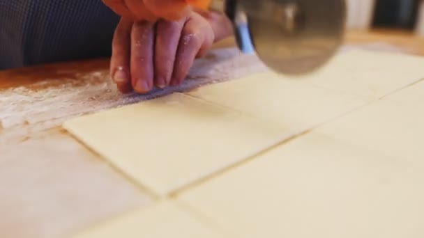 Panadero corta masa con cuchillo de pizza en la mesa en primer plano panadería — Vídeos de Stock