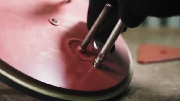 Werkschroeven plakken op rood metalen detail op houten tafel — Stockvideo