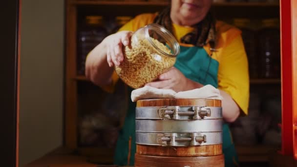 Dame giet rauwe pijnboompitten in olie extractor op houten tafel — Stockvideo