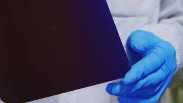 Εργάτης σε ρόμπα δείχνει πολύχρωμο μέρος του ηλιακού πάνελ στο κατάστημα — Αρχείο Βίντεο