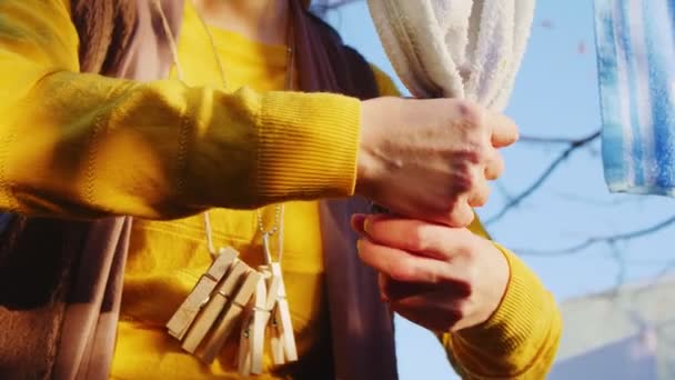 Домогосподарка в жовтому рушнику на мотузці у дворі крупним планом — стокове відео