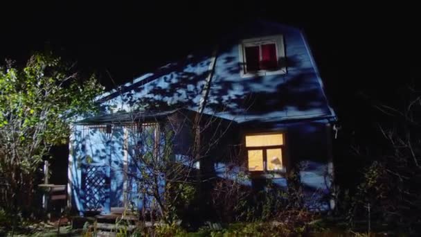 Gebouw met blauwe muren en verlichte raam tegen donkere lucht — Stockvideo