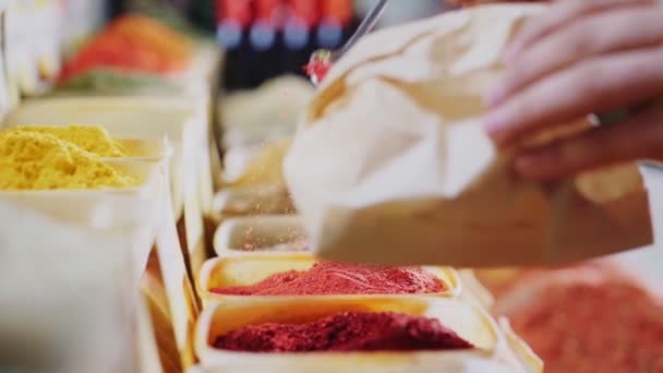 Woman puts spices into paper bag from showcase closeup — Stock Video