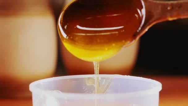 Delicious honey pours from rustic wooden spoon macro — Stock Video