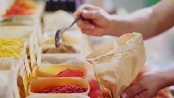 Saleswoman fills paper bag with ground paprika at store — 비디오