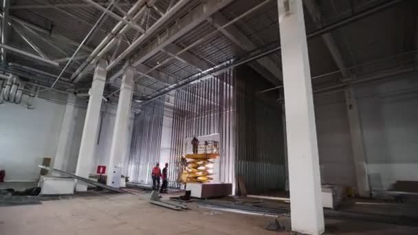 Építők csapat ollóval lift telepíti deszkák a raktárban — Stock videók
