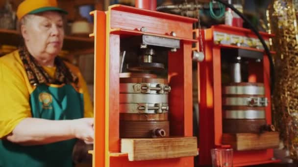 Woman installs pot with tap to oil press machine at market — Stockvideo