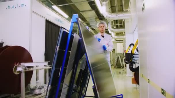 Empregado carrega rack com painéis solares ao longo da oficina da planta — Vídeo de Stock