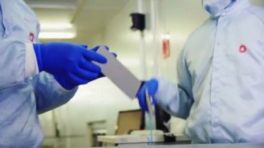 employees cover solar panel cell with material in workshop
