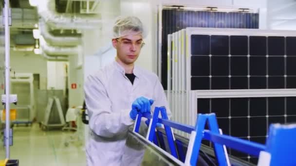 Travailleur dans le transport de lunettes panneaux solaires le long de l'atelier — Video