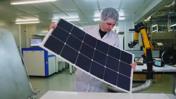 Квалифицированный работник изгибает солнечную панель возле белого стола на заводе — стоковое видео
