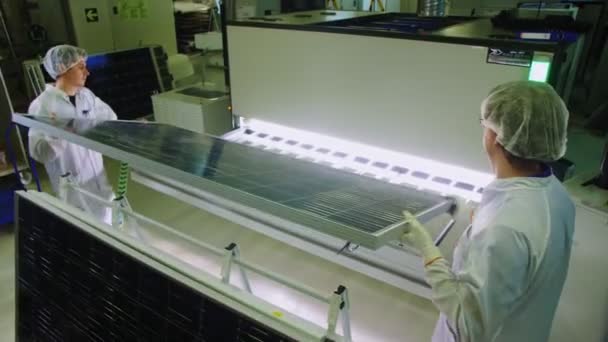 Anställda sätter solpanel i låda med blylampor i butik — Stockvideo