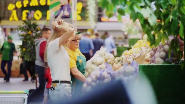 Женщина покупает лук у зрелой продавщицы на фермерском рынке — стоковое видео