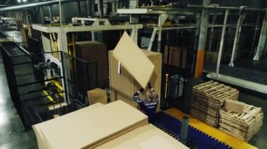Kadın işçi atölyeye karton paket kağıdı koyar.